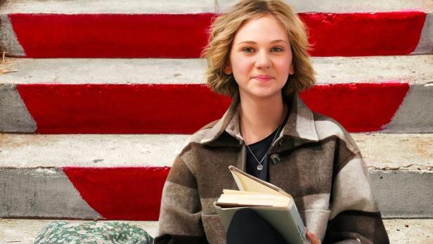 Eine junge Frau sitzt auf einer Treppe und liest ein Buch; Filmposter für „Life By Ella“.