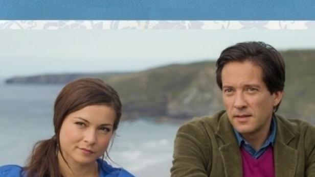 Das Cover des Films „Besetzte Herzen“ aus der Rosamunde Pilcher Collection mit zwei Schauspielern vor einer Küstenlandschaft.