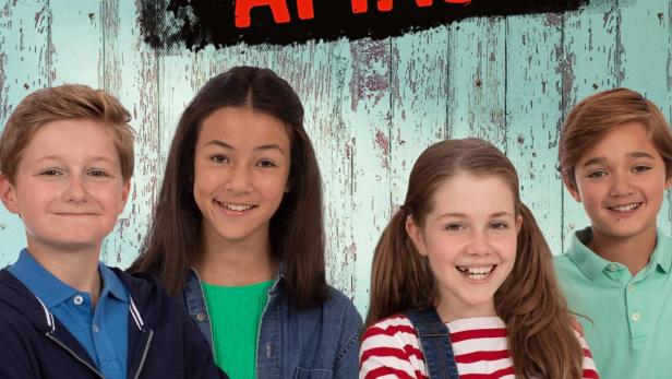 Das Poster für „Gag Attack“ zeigt vier lächelnde Kinder vor einem hölzernen Hintergrund.