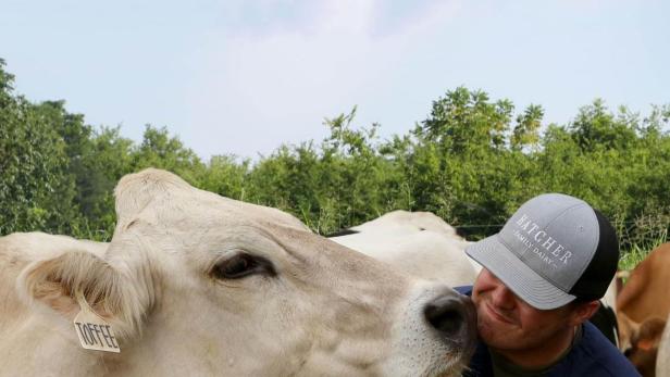Ein Mann umarmt eine Kuh namens Toffee auf der Hatcher Family Dairy Farm.