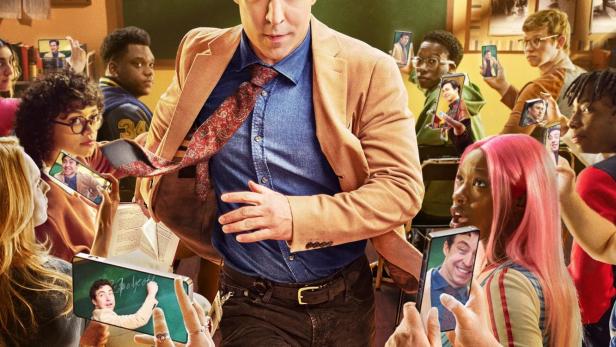 Ein Englischlehrer eilt durch eine Klasse, während Schüler ihn mit ihren Handys filmen.