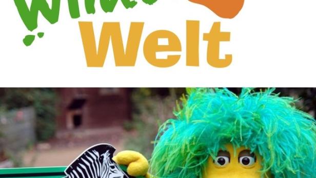 Ein gelbes Löwen-Stofftier mit grüner Mähne steht neben einem Schild mit einem Zebra.