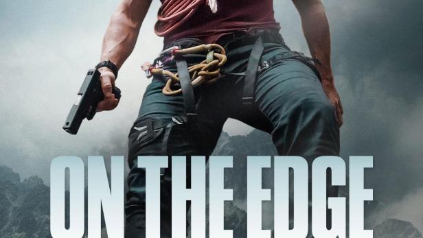 Ein Mann mit einer Pistole und Kletterausrüstung steht vor einer Bergkulisse für „On the Edge: Showdown in den Bergen“.