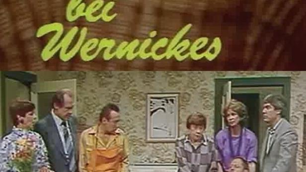 Szene aus „Tumult bei Wernickes“ mit einer Gruppe von Menschen in einem Wohnzimmer.