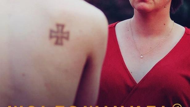 Eine Frau in Rot steht neben einem Mann mit einem Tattoo auf dem Rücken.