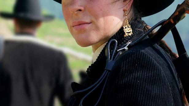 Eine junge Frau in traditioneller Tracht vor einer Bergkulisse, möglicherweise eine Szene aus „Auf der Walz: Drei Jahre und ein Tag“.