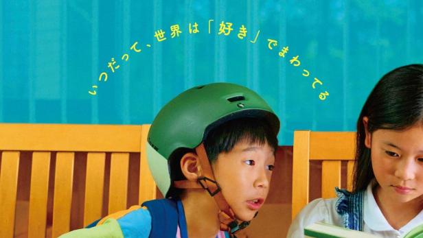 Ein Junge mit Fahrradhelm liest mit einem Mädchen zusammen in einem Buch.