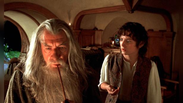Gandalf raucht Pfeife, während Frodo ihn aufmerksam beobachtet.