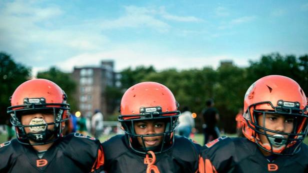 Drei junge Footballspieler der Brooklyn Saints stehen nebeneinander.