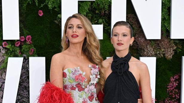 Blake Lively und Isabel Ferrer posieren zusammen vor einer Wand aus Blumen.