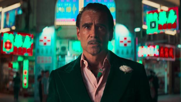 Colin Farrell in einer Filmrolle nachts vor Leuchtschildern in Macao.