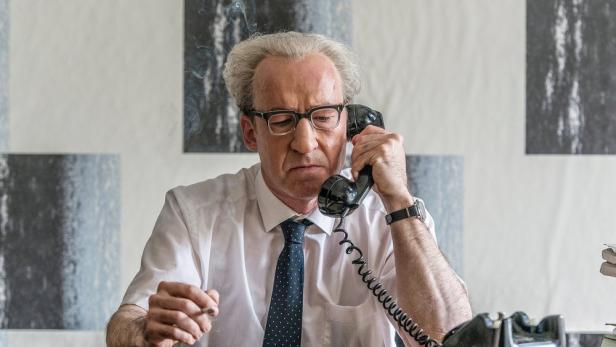 Mann mit Telefonhörer am Ohr sitzt im Büro.