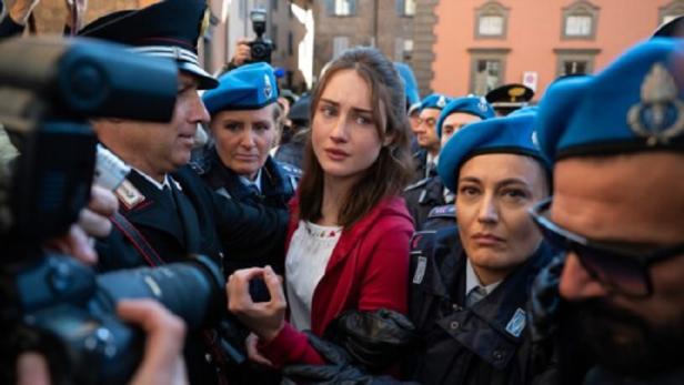 Seriendarstellerin der Amanda Knox von Polizisten umringt, während die Presse sie fotografiert.