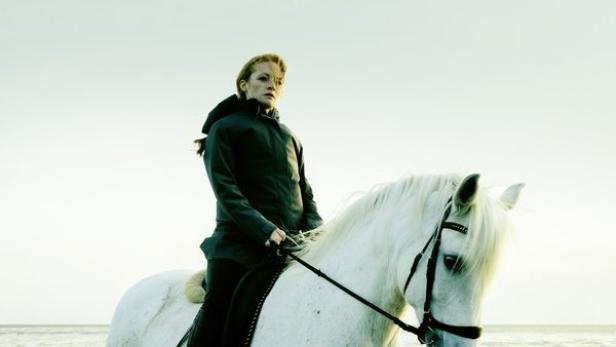 Das Cover des Films „Die Flut – Tod am Deich“ zeigt eine Frau auf einem weißen Pferd am Strand.