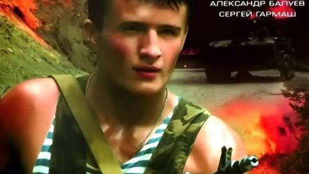 Ein Soldat mit einer Waffe vor einem brennenden Hintergrund, vermutlich eine Szene aus dem Film „Marsch-Brosok“.