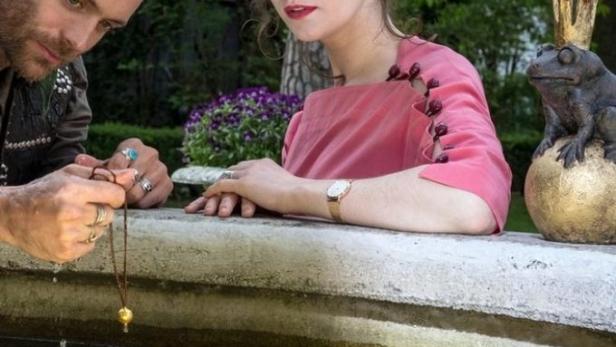 Ein Mann und eine Frau am Brunnen mit einer Froschstatue mit Krone.