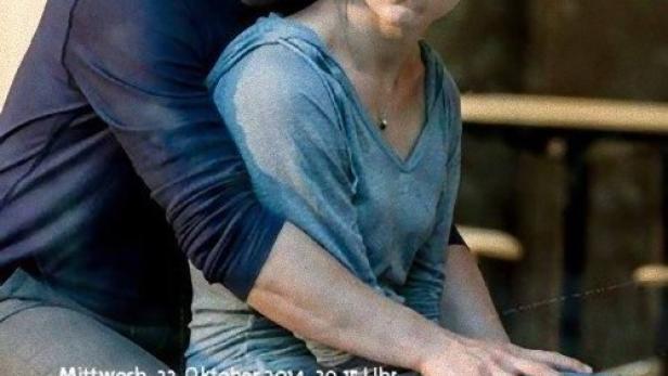 Ein Mann umarmt eine Frau, beide sitzen auf einer Bank.