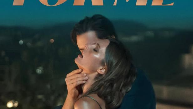 Ein Paar umarmt sich innig vor einer nächtlichen Stadtkulisse, über dem Titel „Fall For Me“.