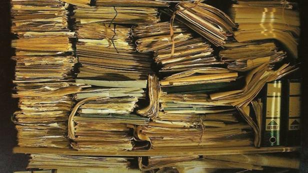 Das Buchcover von „Das Schloss“ nach Franz Kafka zeigt einen Stapel alter Dokumente.