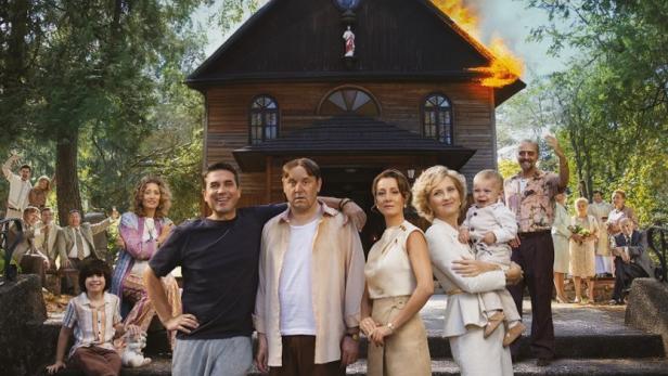 Das Filmplakat für „Teściowie 3“ zeigt die Besetzung vor einer brennenden Kirche.