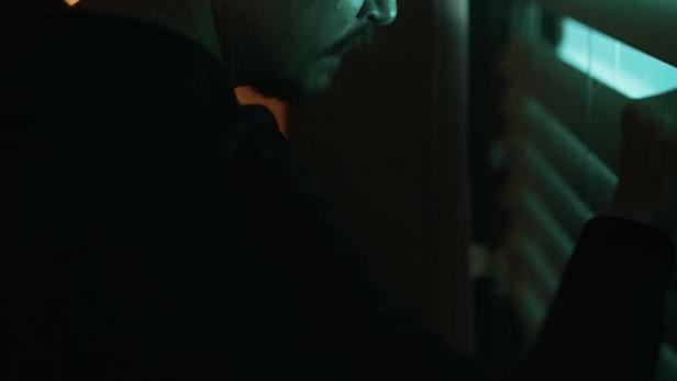 Das Filmplakat für „Just Breathe“ zeigt Shawn Ashmore, der durch Jalousien blickt.