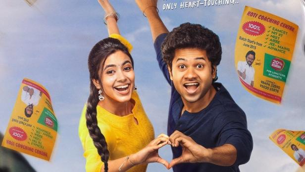 Ein Mann und eine Frau formen mit ihren Händen ein Herz vor dem Filmposter „Little Hearts“.