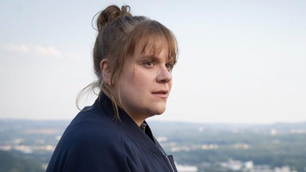 Stefanie Reinsperger in ihrer Tatort-Rolle steht auf erhöhtem Platz mit einer unscharfen Landschaft im Hintergrund.