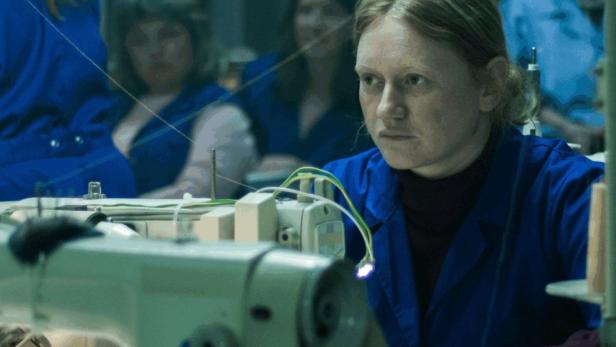 Eine Schneiderin arbeitet an einer Nähmaschine; Filmposter für „Made in EU“.