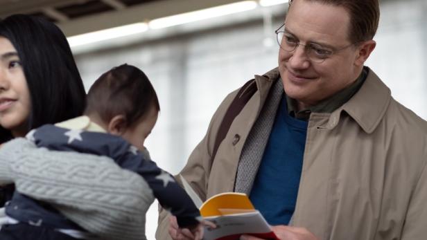 Brendan Fraser hält in Filmrolle ein aufgeschlagenes Buch in der einen Hand und fasst mit der anderen die ausgestreckte Hand eines Kleinkinds.