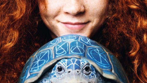 Mädchen, das eine fantastische blaue Schildkröte auf den Handflächen hält.