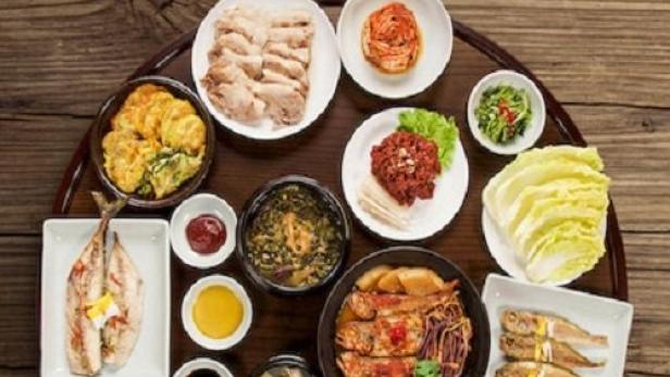 Eine Auswahl an koreanischen Beilagen (Banchan) auf einem Holztablett angerichtet.