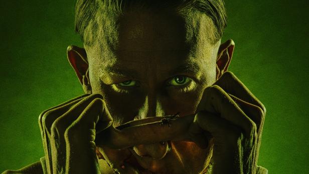 Schauspieler Charlie Hunnam zieht sich in seiner Rolle als Serienkiller Ed Gein eine Hautmaske über das Gesicht.