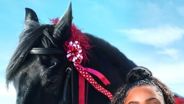 Das Filmplakat zu „Free Rein: Valentine's Day“ zeigt ein Mädchen und ein geschmücktes schwarzes Pferd am Strand.