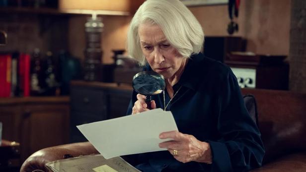 Helen Mitten untersucht mit einer Lupe eine Fotografie in „The Thursday Murder Club“.