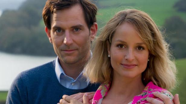 Das Cover von Rosamunde Pilchers „Ungezügelt ins Glück“ zeigt ein Paar vor einer Küstenlandschaft.