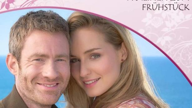 Das Filmplakat zu „Rosamunde Pilcher – Pralinen zum Frühstück“ mit einem Paar vor dem Meer.