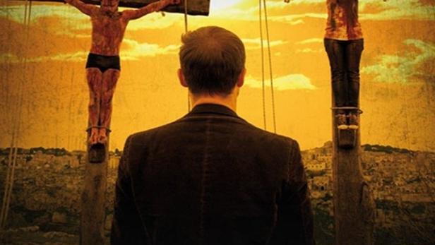 Ein Mann blickt auf zwei gekreuzigte Personen im Film „Ausgelöscht – Ascension Day“.