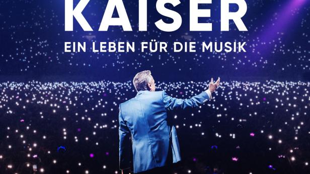Roland Kaiser steht auf dem Filmplakat auf der Bühne vor einem Lichtermeer im dunklen Zuschauerraum.