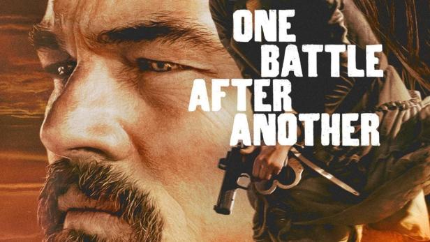 Ein Filmposter zeigt eine Frau mit einer Waffe vor dem Gesicht eines Mannes und einer Wüstenstraße.