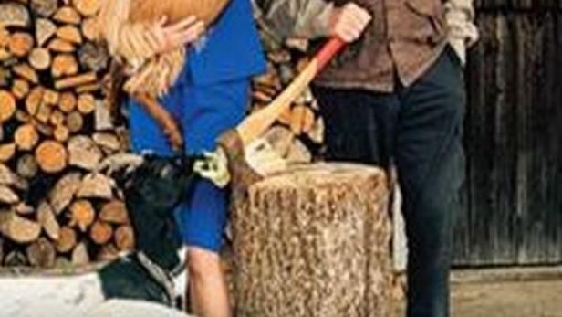 Eine Frau im Kostüm hält eine Ziege, während ein Mann mit Hut daneben steht.