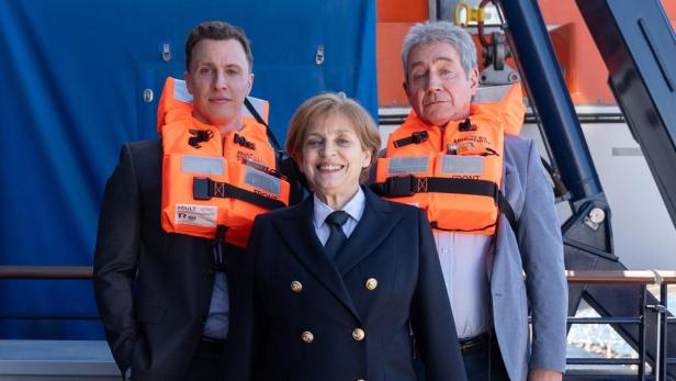 Katharina Thalbach als „Miss Merkel“ in Kapitänsuniform auf einem Kreuzfahrtschiff.