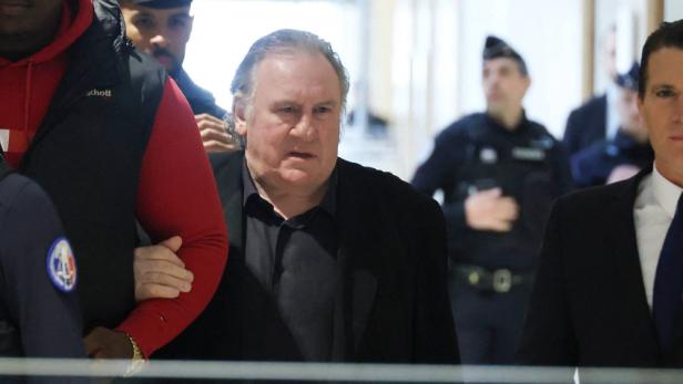 Gérard Depardieu betritt ein Gerichtsgebäude neben seinem Anwalt.