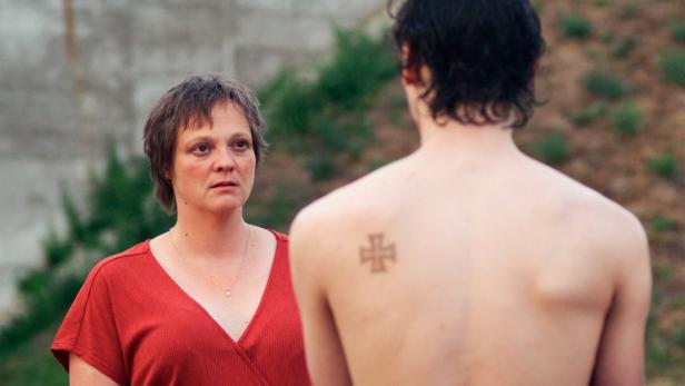 Eine Frau steht vor einer anderen Person, von der nur deren nackter Rücken sichtbar ist.