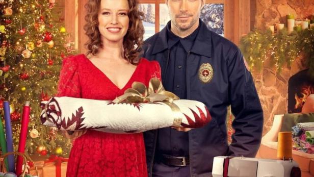 Filmposter für „Der Weihnachtsquilt“ mit Ferelith Young und Harmon Walsh vor weihnachtlichem Hintergrund.