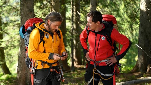 Markus Brandl und Sebastian Ströbel bereiten sich in „Die Bergretter“ im Wald für eine Rettungsaktion vor.