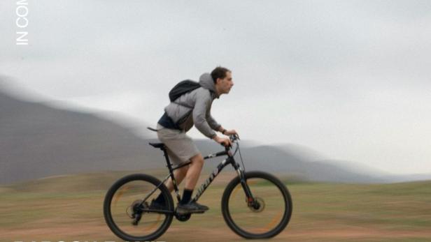 Ein Mann fährt mit einem Mountainbike durch eine hügelige Landschaft.
