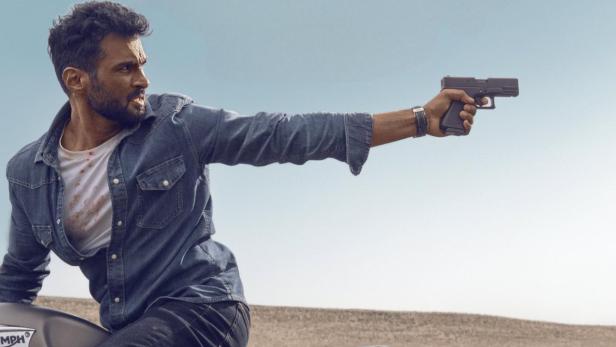 Ein Mann auf einem Motorrad zielt mit einer Pistole in die Luft.