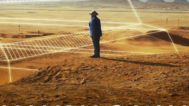 Ein Mann steht in der Wüste vor einer computergenerierten Darstellung einer Pyramide.