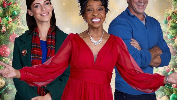 Das Filmplakat für „I'm Glad It's Christmas“ zeigt drei lächelnde Darsteller vor Weihnachtsbäumen.