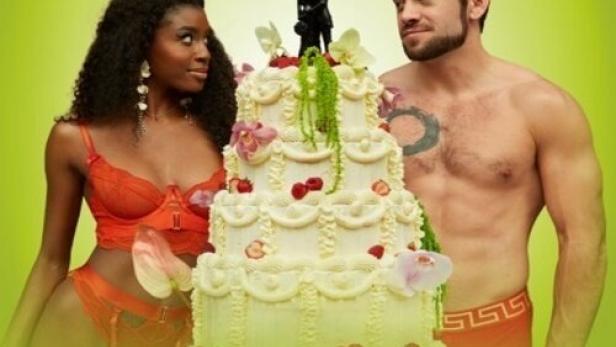 Ein Paar in Unterwäsche steht neben einer Hochzeitstorte vor einem grünen Hintergrund.